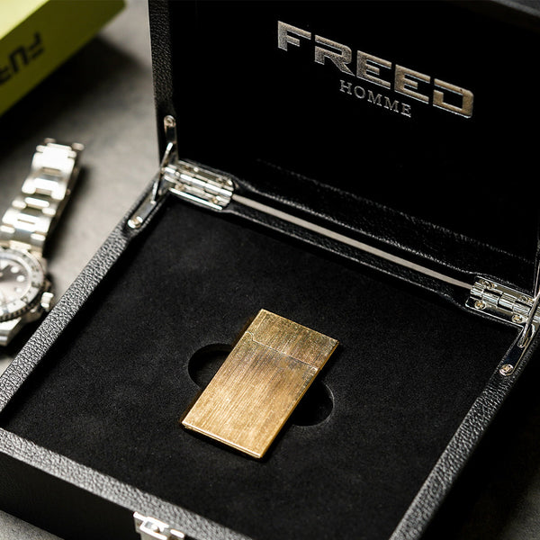 金色拉絲銅殼打火機,俯視角度,置於黑色盒內。FREED 客製化刻字。